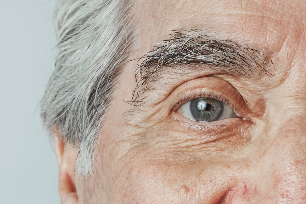 Close-up of an older adult’s eye with visible details of the iris, eyelashes, and skin.