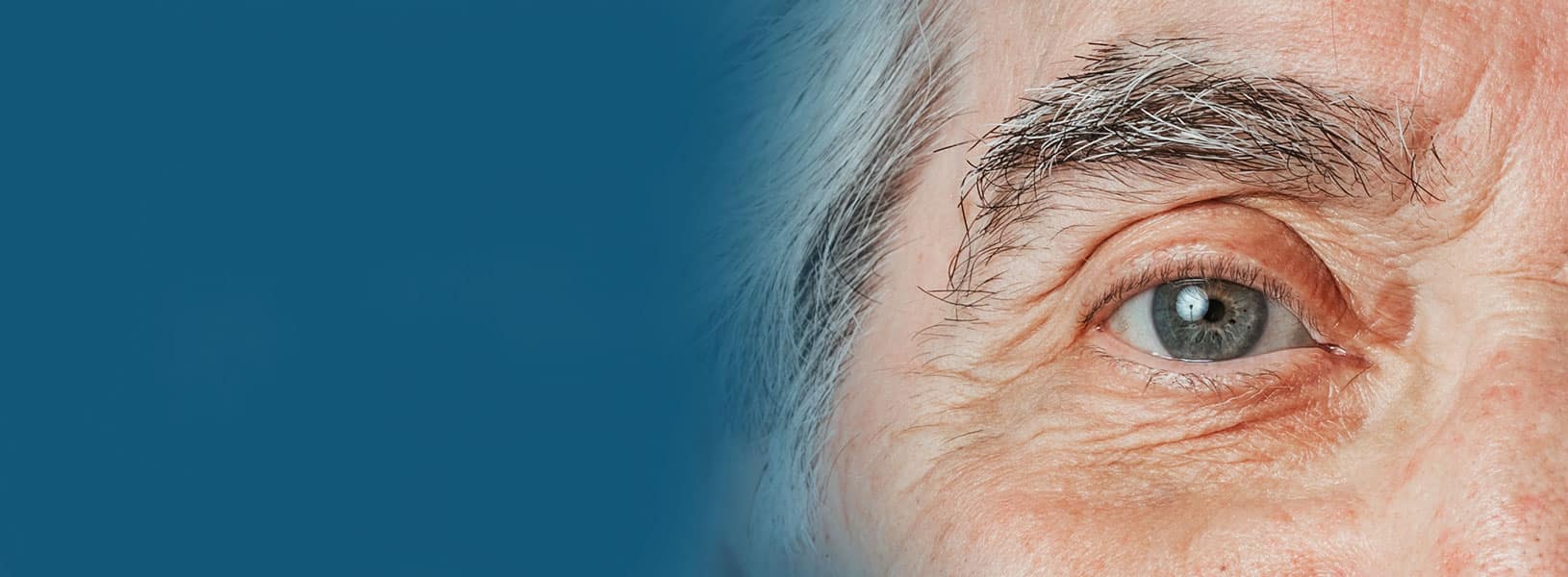 Close-up of an older adult’s eye with visible details of the iris, eyelashes, and skin.