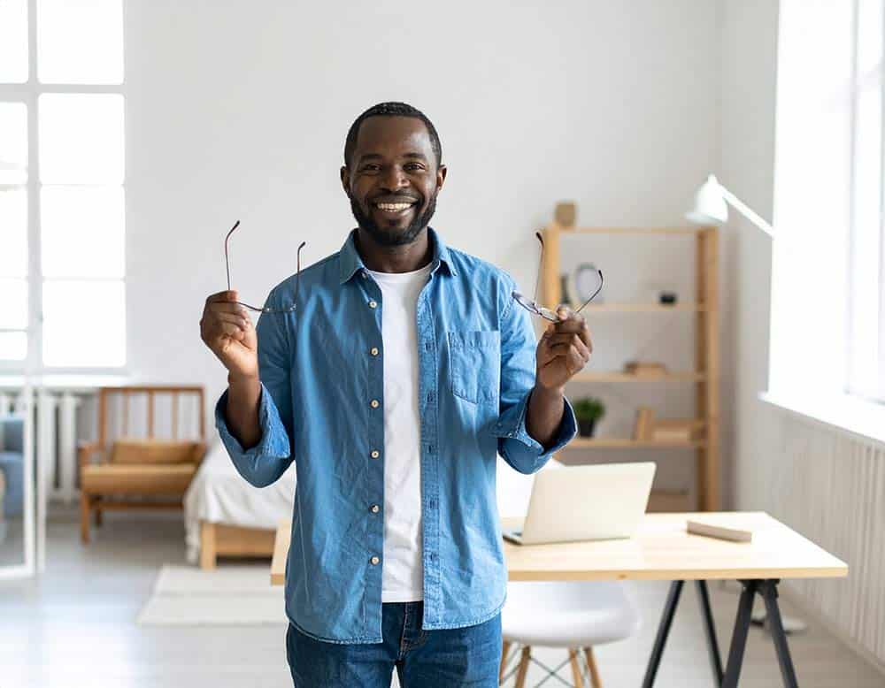 African american man showing his glasses in excitement to get rid of them for RLE surgery.