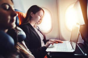 Female passenger working on laptop in an airplane