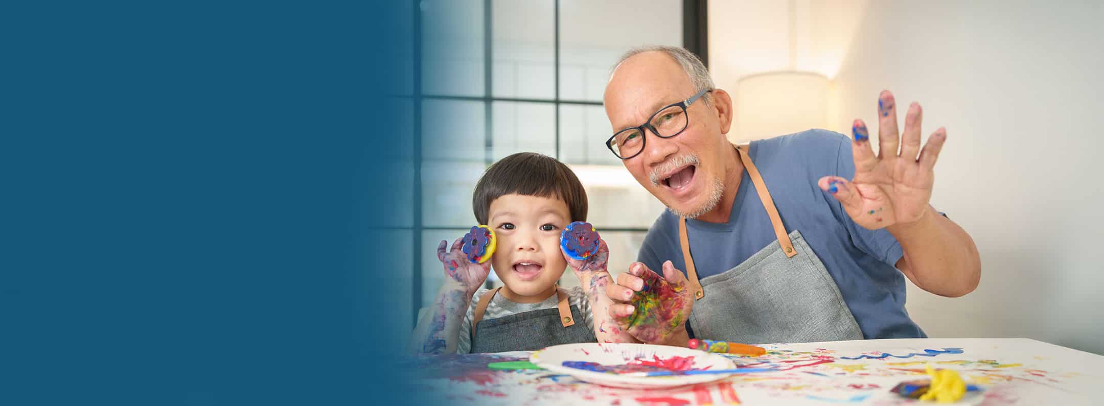 Grandfather with glasses and a young child painting together, showing healthy vision and joyful family moments.