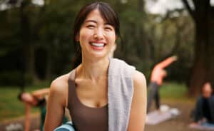 25 year old Asian woman enjoying yoga in the park after finding the best LASIK surgeon in Arizona at Barnet Dulaney Perkins.
