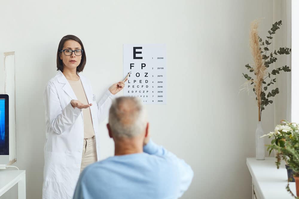 Ophthalmologist pointing at eye chart while testing 20/20 vision.