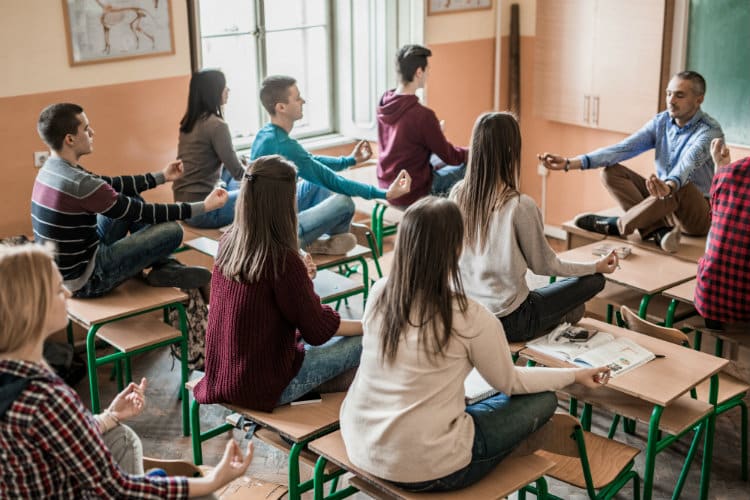 group of students with their professor meditating in a classroom