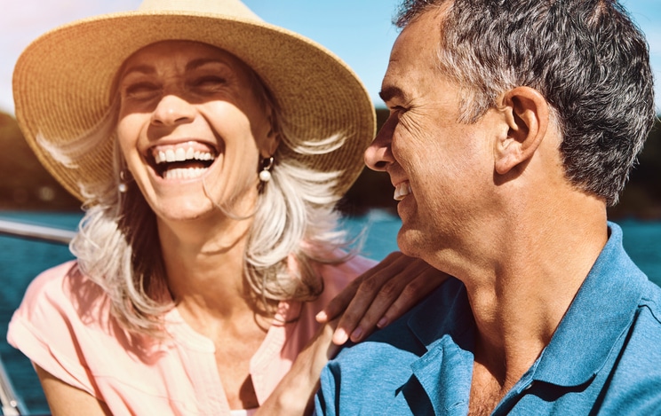 Smiling older couple wearing sun hats and talking about cataract surgery options.