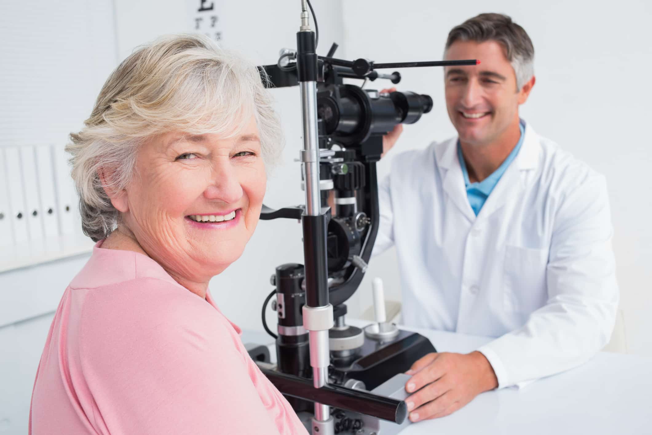 Portrait of senior woman smiling while sitting with optician in clinic