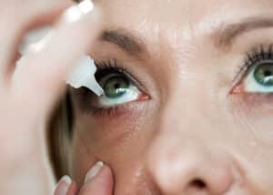 close-up of a person applying lubricating eye drops to relieve dry eye as a cause of blurry vision