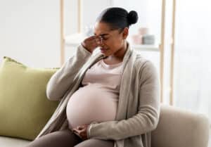 Pregnant woman experiencing headache and light sensitivity during pregnancy