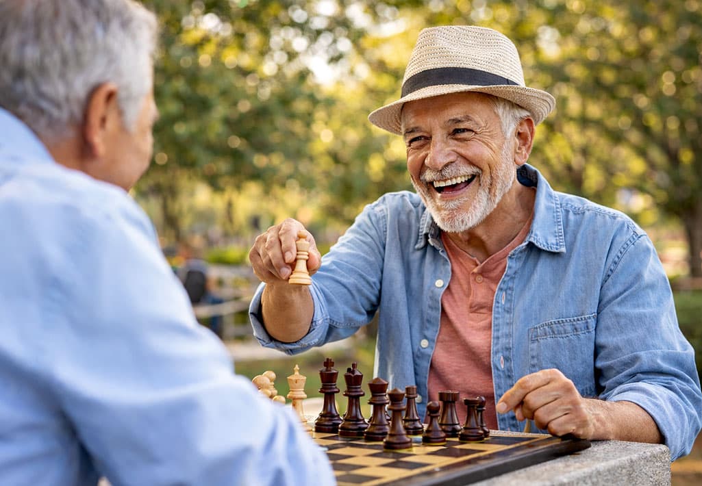 Senior man playing chess with his best friend after macular hole treatment at Barnet Dulaney Perkins.