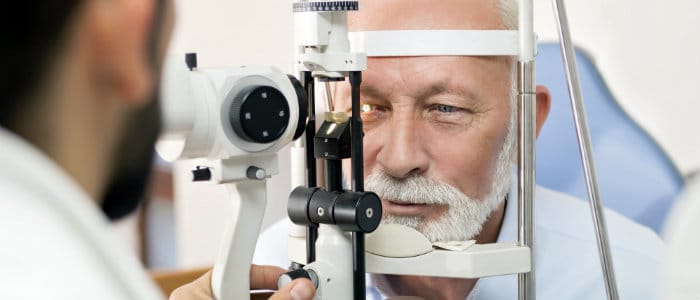 Optometrist examining senior man's eyes with glaucoma