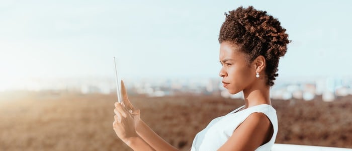 Woman squinting at tablet showing signs you may need an eye exam