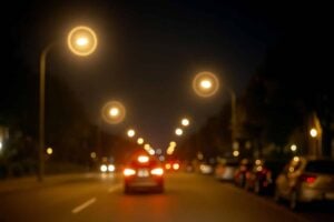 POV view of streetlights and car headlights with bright halos and glare, early signs of cataracts
