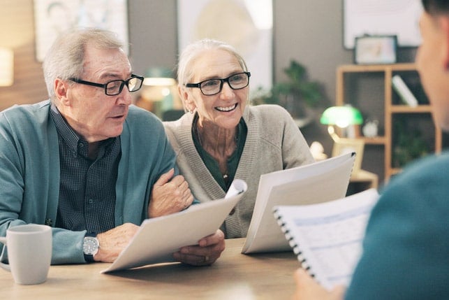 Elderly couple reviewing documents with an advisor as part of 31 Answers to Your Cataract Surgery Questions