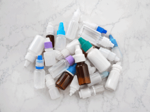 Assorted eye drop bottles on a tabletop, illustrating artificial tears for dry eyes at Barnet Dulaney Perkins Eye Center.