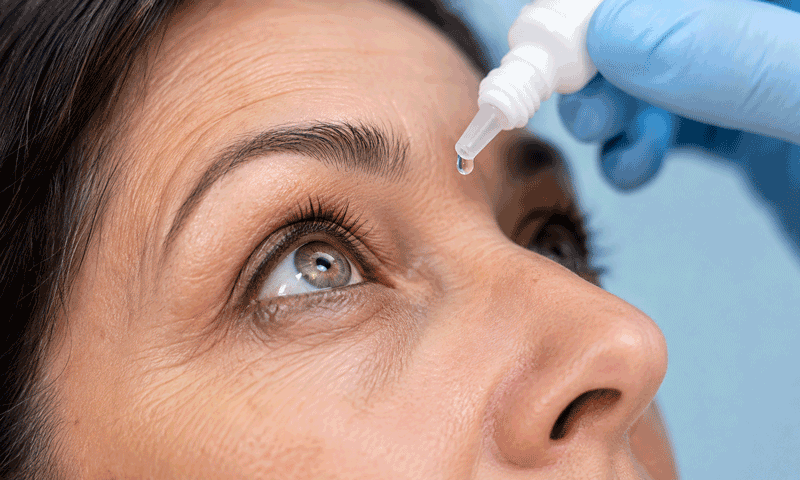 Close-up of a woman’s eye beneath an eye dropper, illustrating retinal imaging vs dilation for Barnet Dulaney Perkins Eye Center.