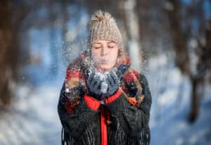 Woman blowing snow outdoors to illustrate how to take care of your eyes this winter