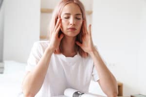 Woman holding her head during a migraine aura illustrating why you keep seeing spots